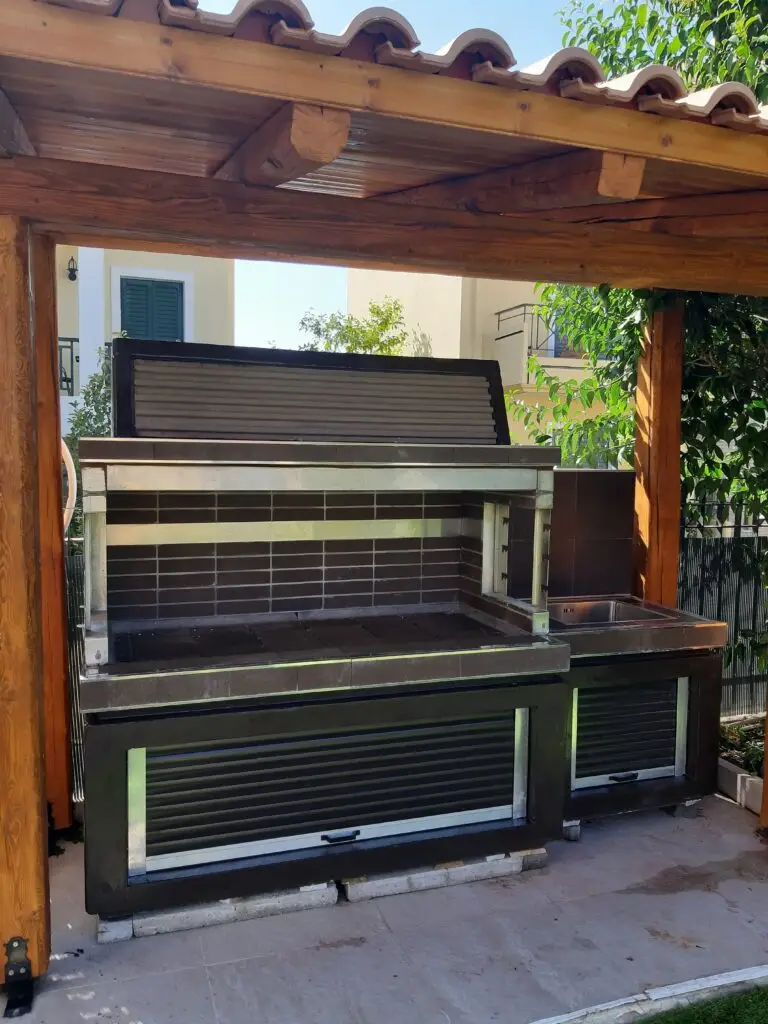 Modern outdoor barbecue station with a built-in sink and storage cabinets, set under a wooden pergola.